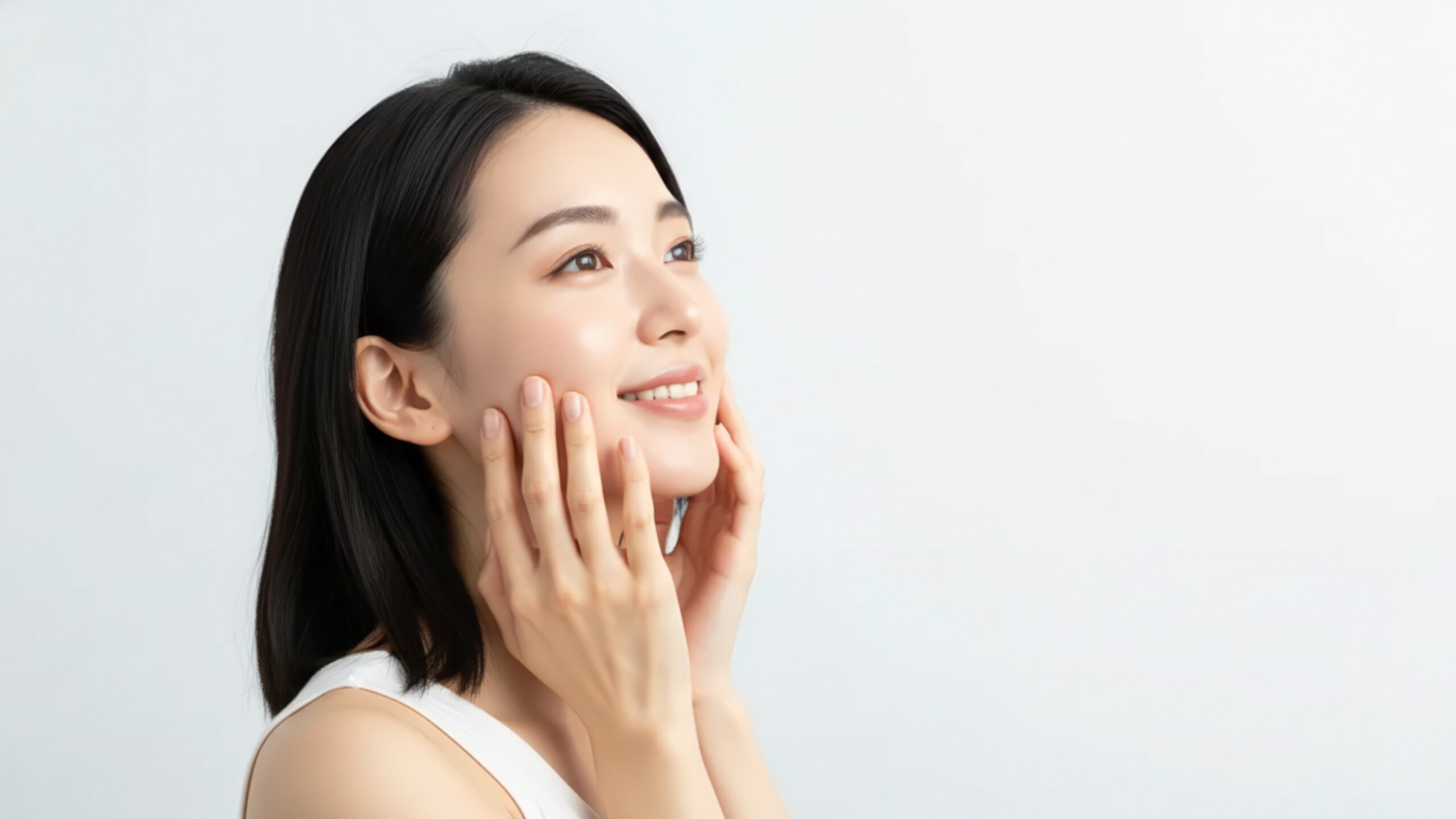 治療を続けやすい価格設定をイメージした、微笑みながら頬に手を添える女性の写真
