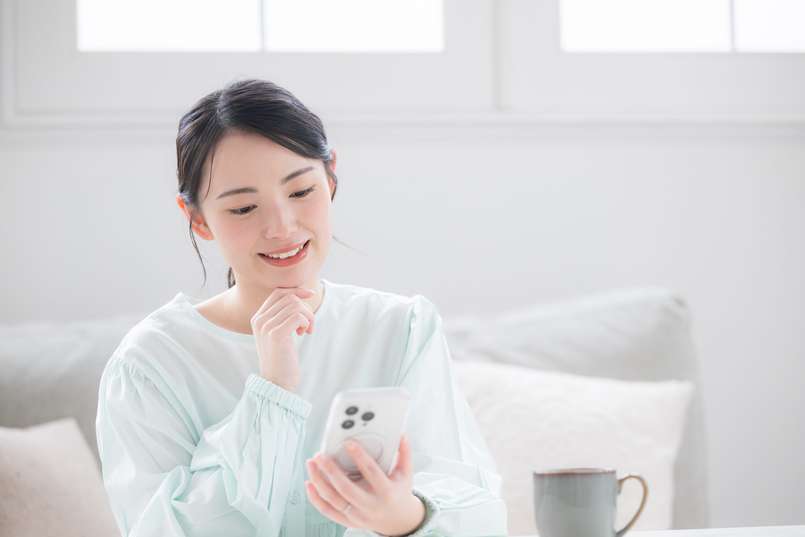緻密なシミュレーションをイメージした、スマートフォンを見ながら考える女性の写真